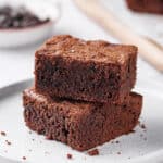 two stacked fudgy homemade brownies on a white plate