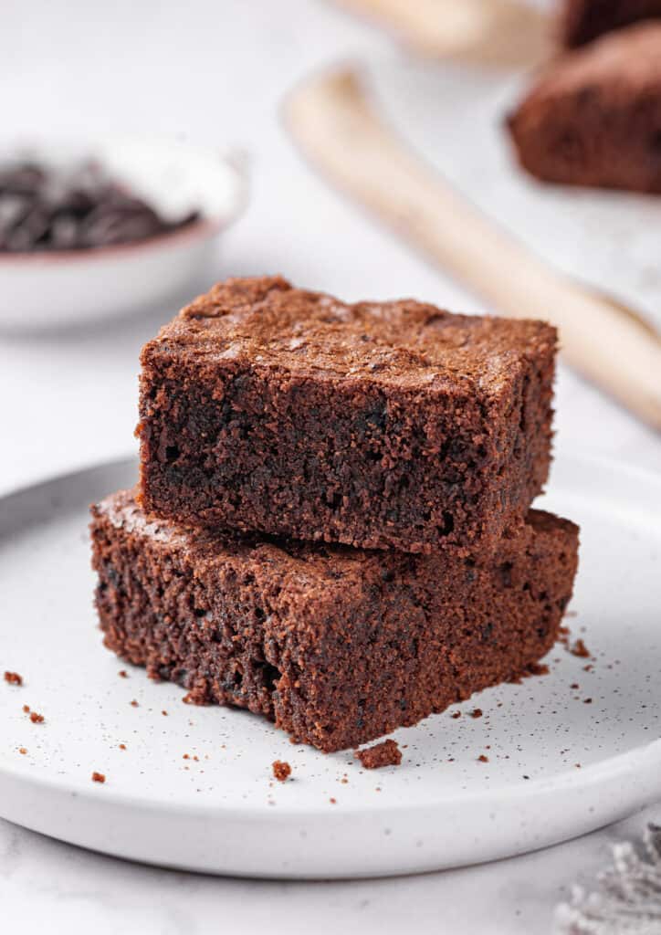 two stacked fudgy homemade brownies on a white plate