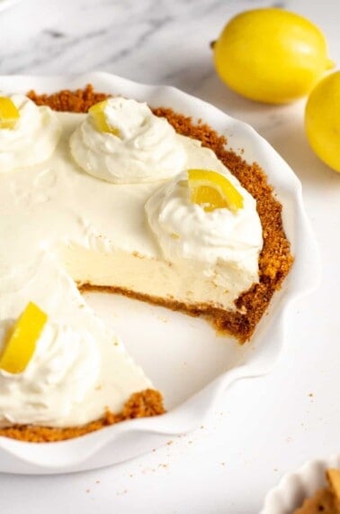 lemon cream pie with graham cracker crust served in a pie dish.