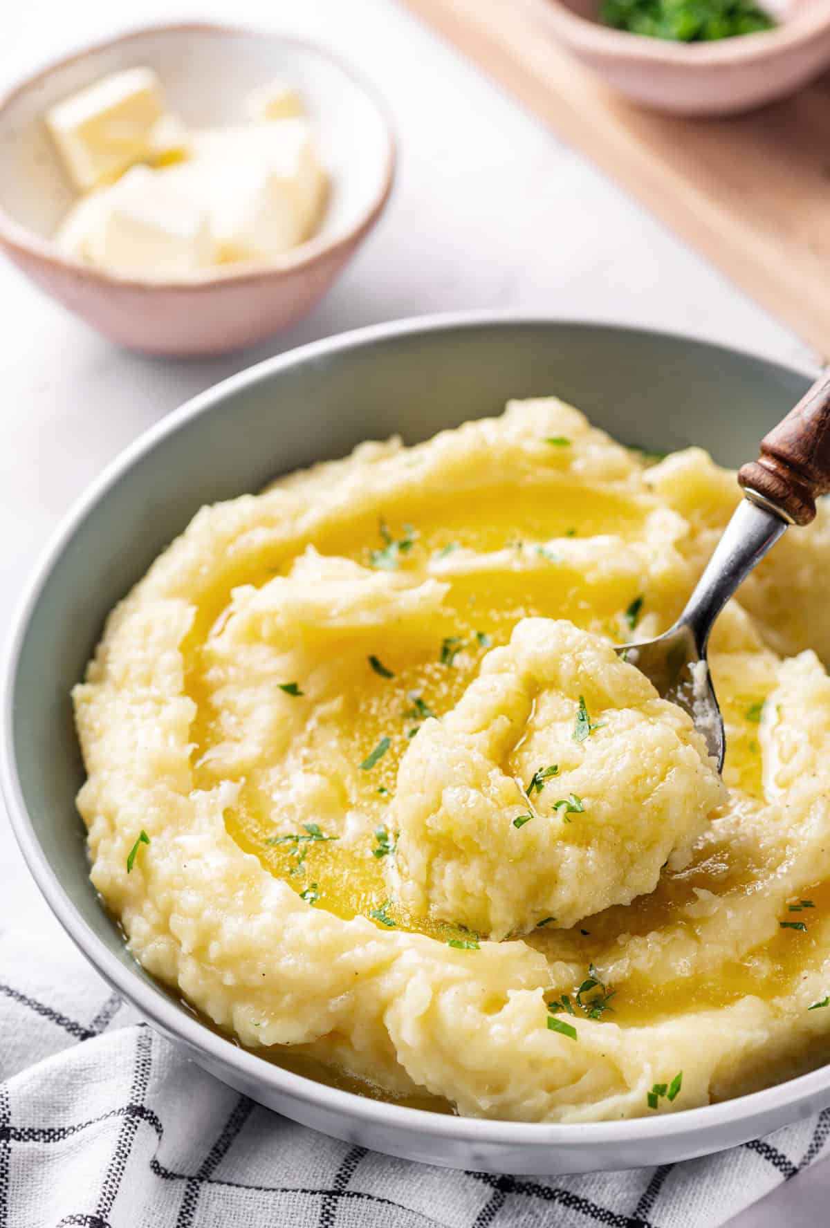 buttery mashed potatoes served in a bowl with a wooden metal spoon