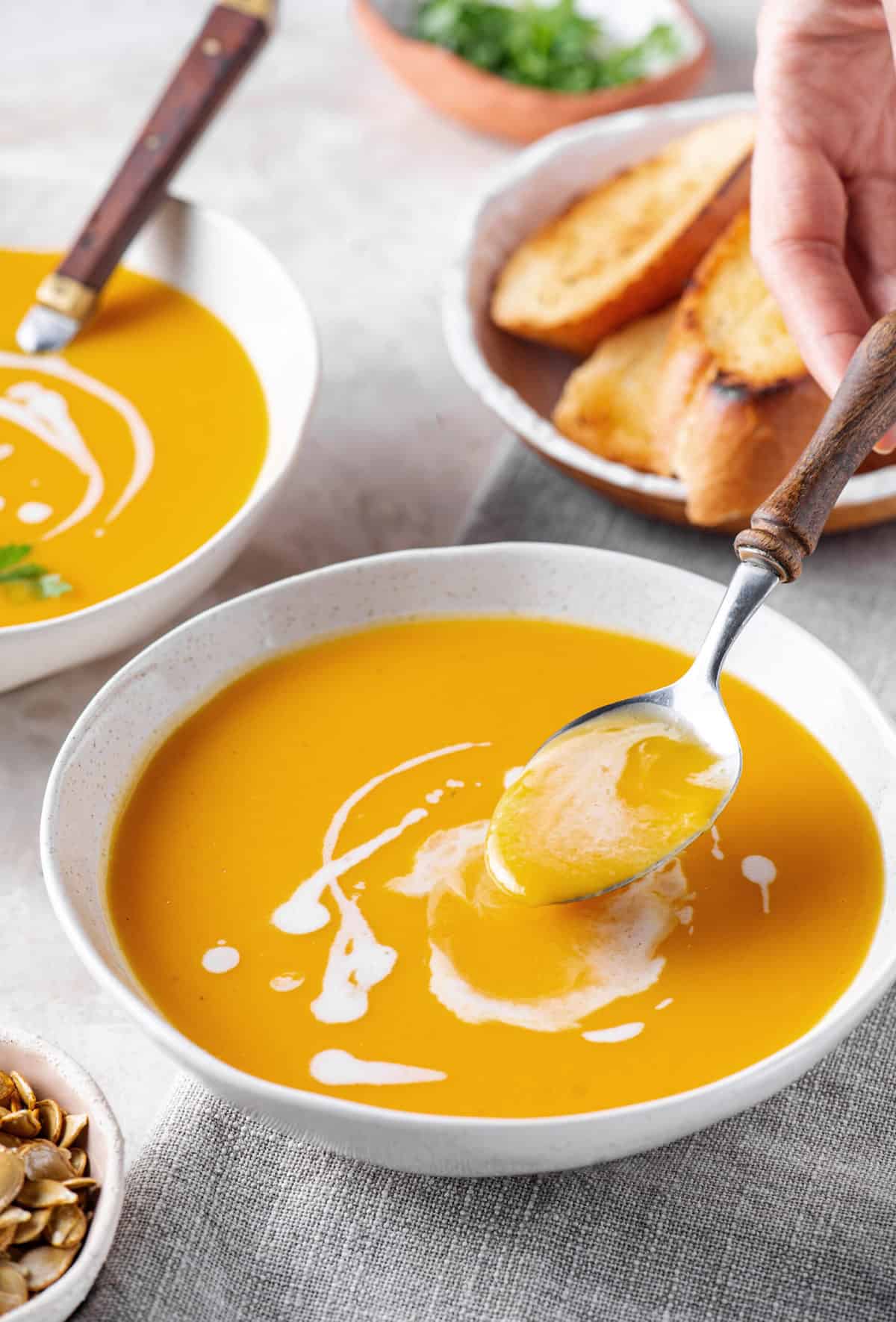 butternut squash soup with spoon served in a white bowl