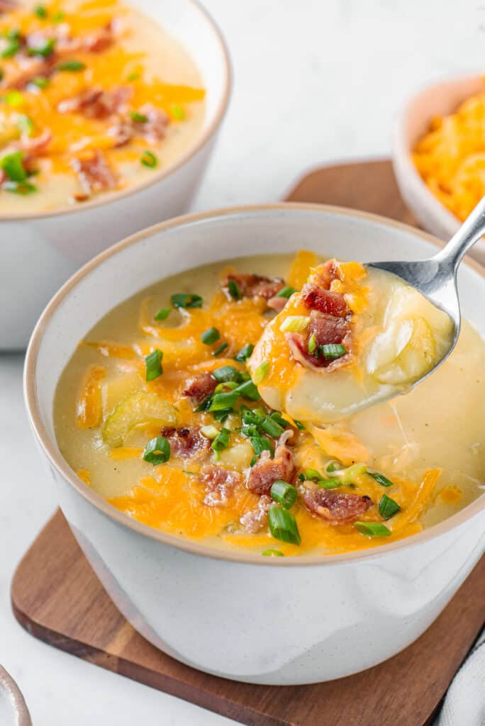 potato soup being dished out on a spoon with cheese and bacon