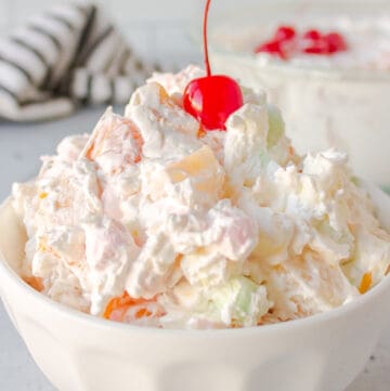 ambrosia salad with a cherry on top served in a white bowl