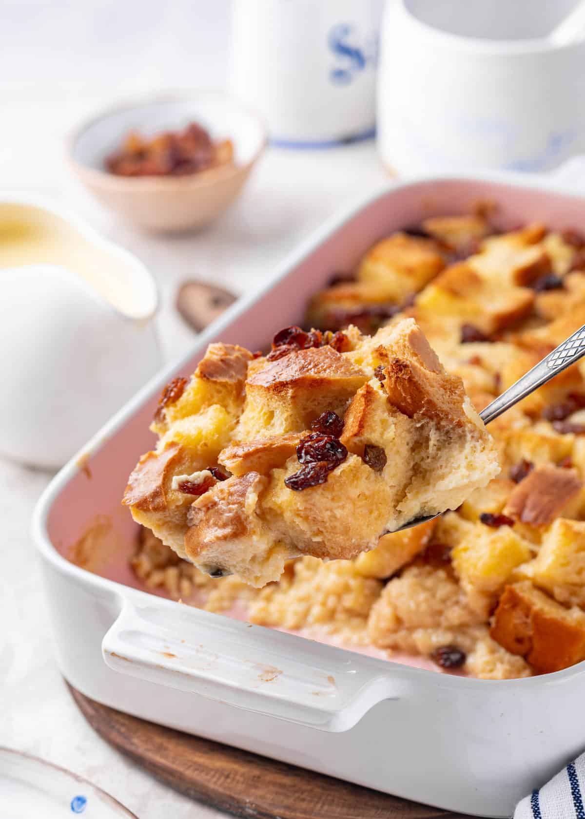 spoonful of bread pudding with casserole dish in the background