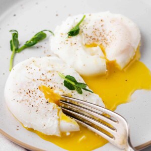 poached egg cut open with a fork served on a plate
