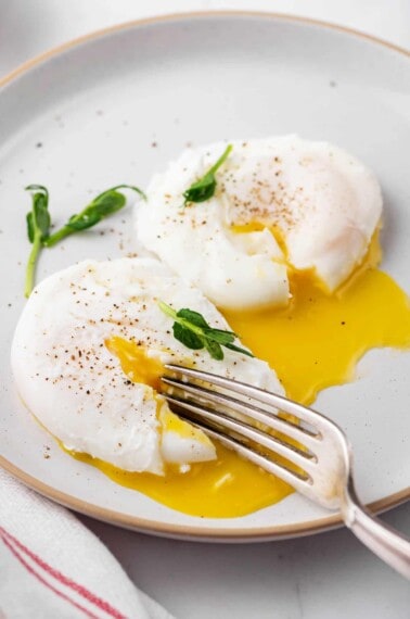 poached egg cut open with a fork served on a plate