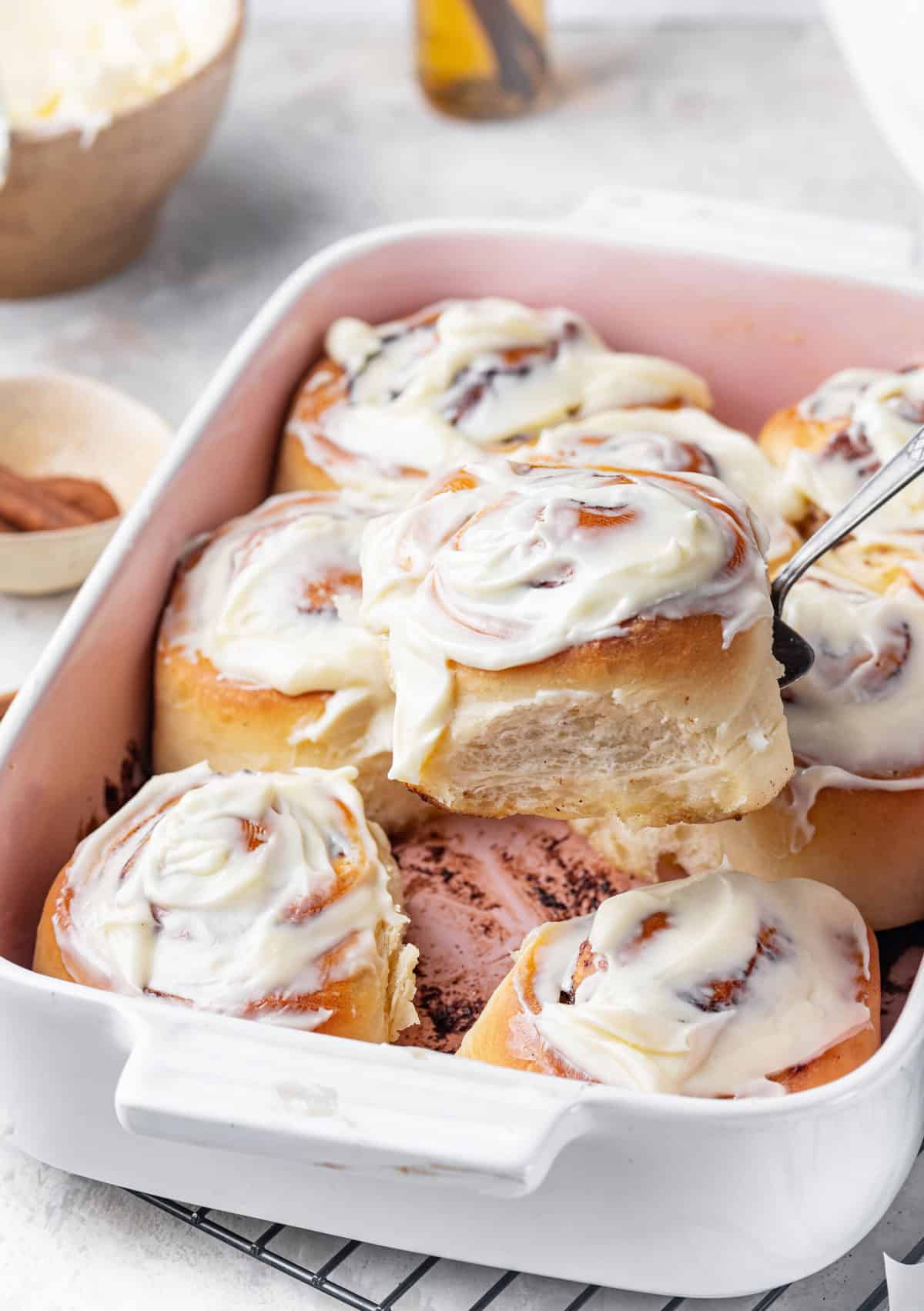 baked cinnamon rolls with cream cheese frosting in a casserole baking dish