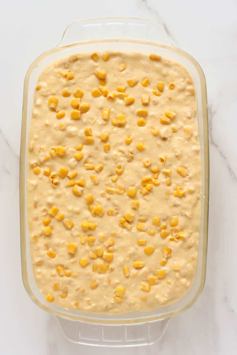 one step to make easy corn pudding  topped with canned corn kernels served in a glass casserole dish