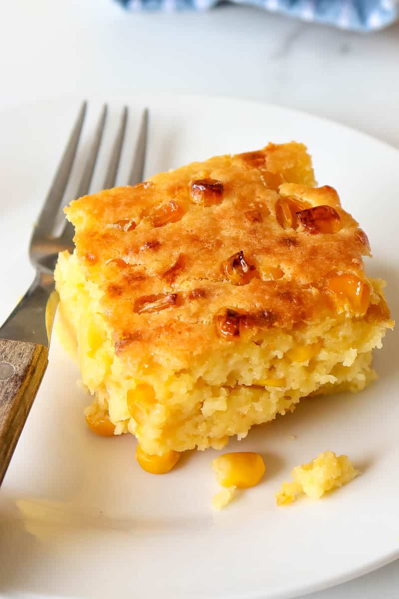 square sliced serving of corn pudding served on a plate with a fork