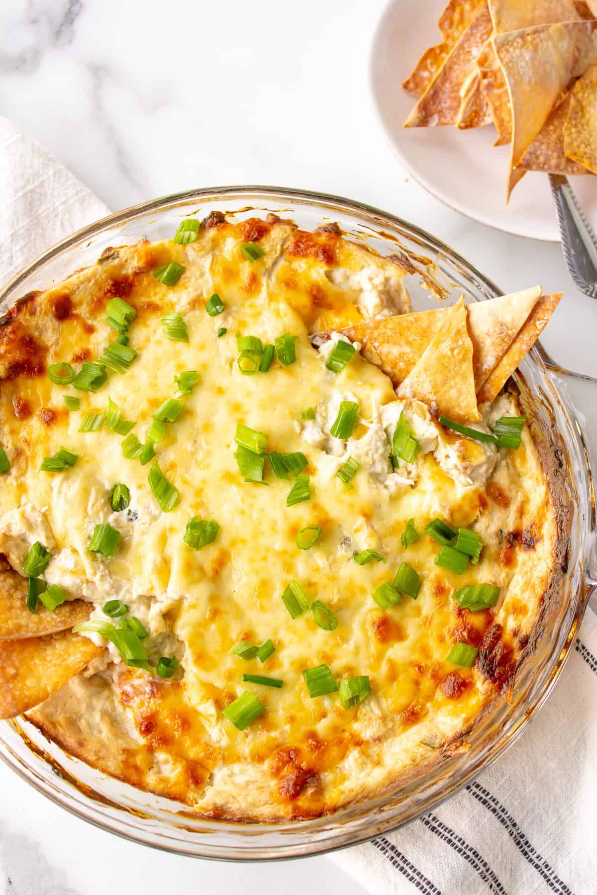 cheesy crab rangoon dip in a glass bowl with wonton chips