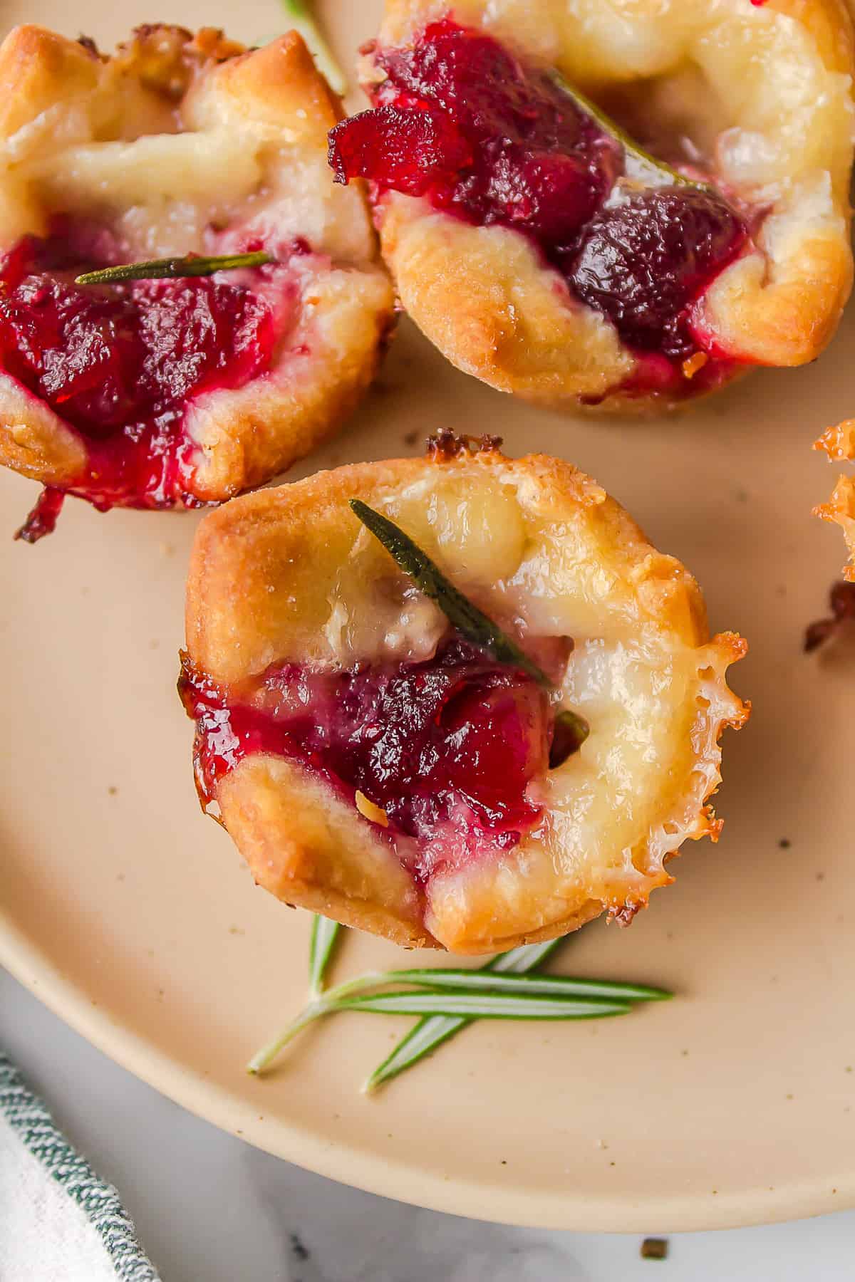baked cranberry brie bite garnished with rosemary served on a plate