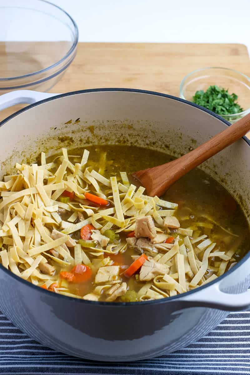 turkey soup in a dutch oven with a wooden spoon