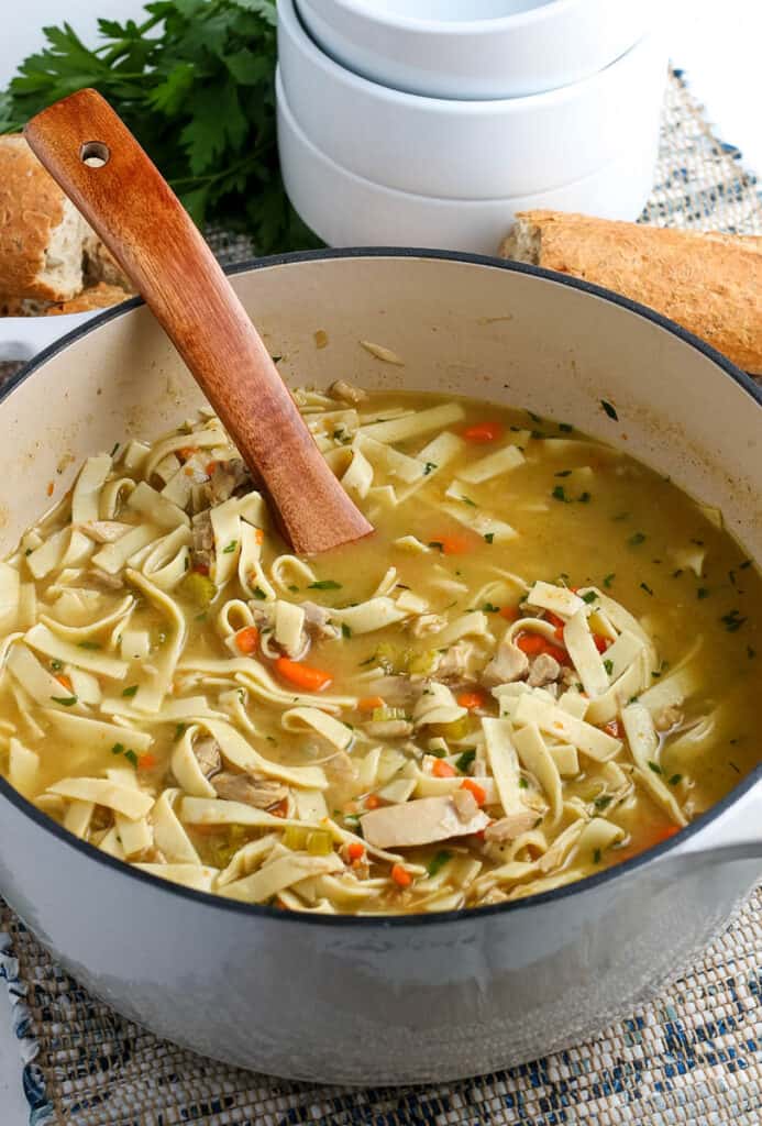 leftover turkey soup in a dutch oven with a wooden soup