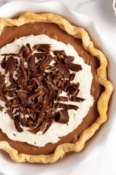 french silk pie with homemade pie crust topped with whipped cream and chocolate curls