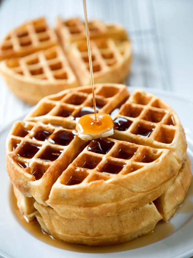 stack of homemade waffles with a slab of butter on top and maple syrup pouring over it