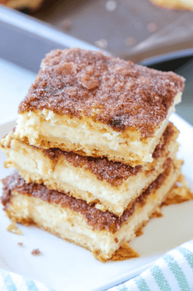 three stacked sopapilla cheesecake bars served on a white plate
