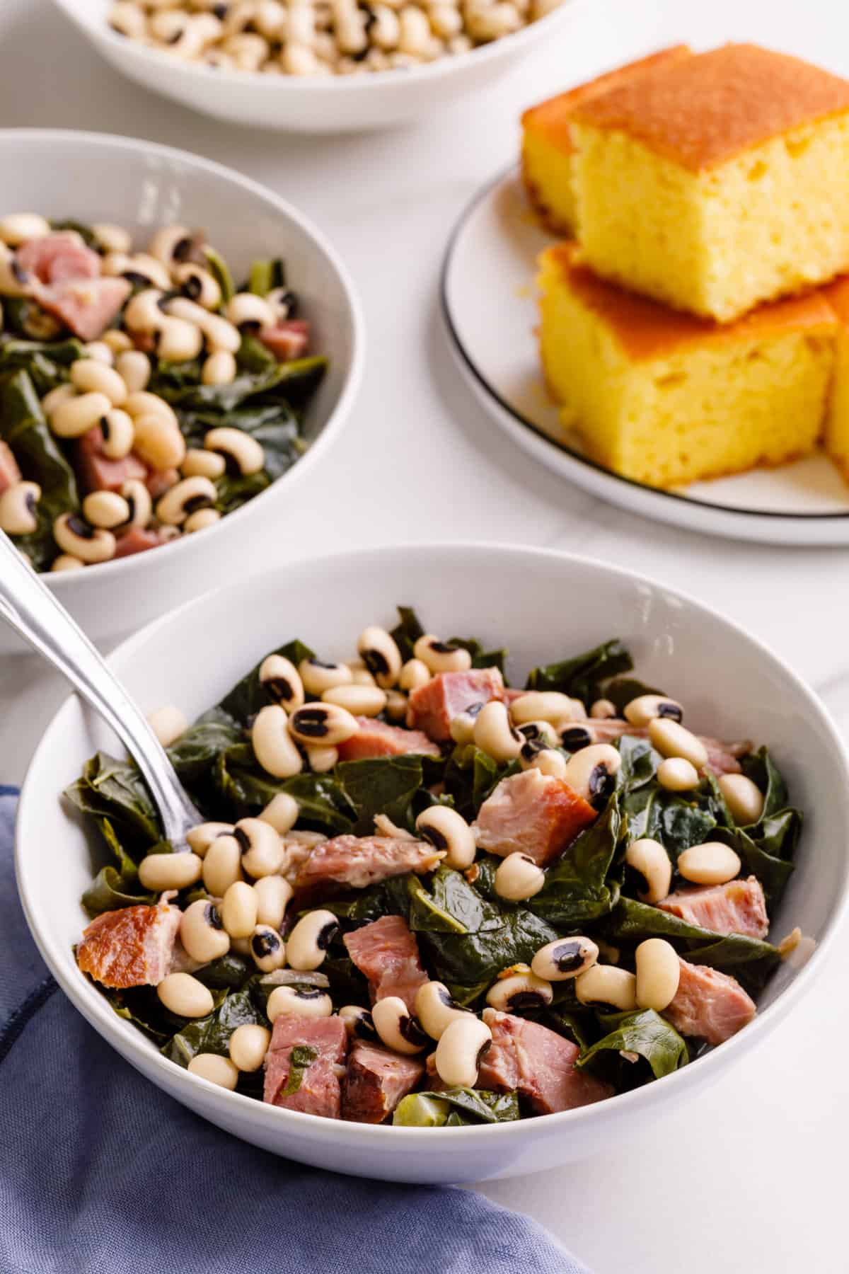 bowl of collard greens, ham and black-eyed peas served in a white round bowl