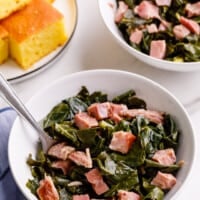 Bowls of Southern-style collard greens next to a plate of cornbread.