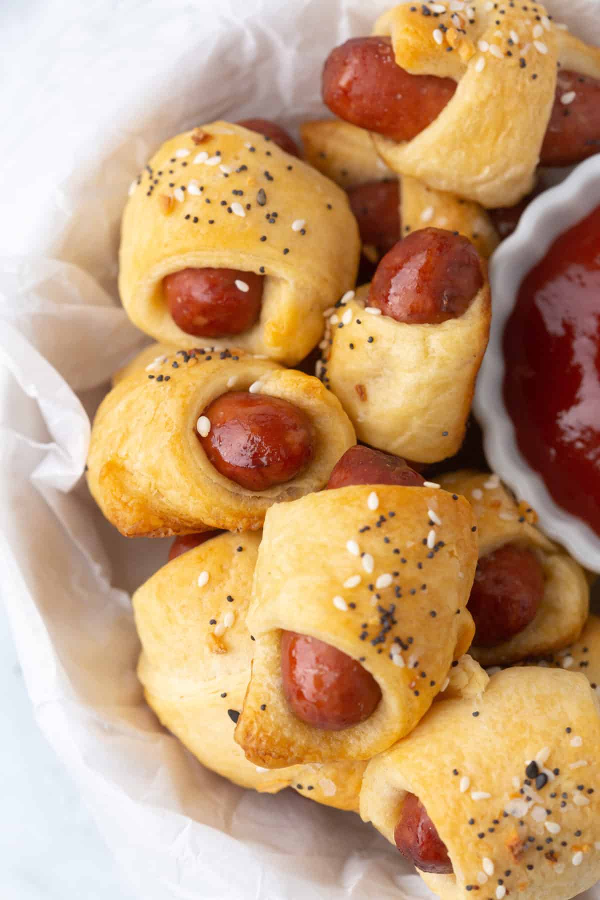 pigs in a blanket in a basket with ketchup on the side