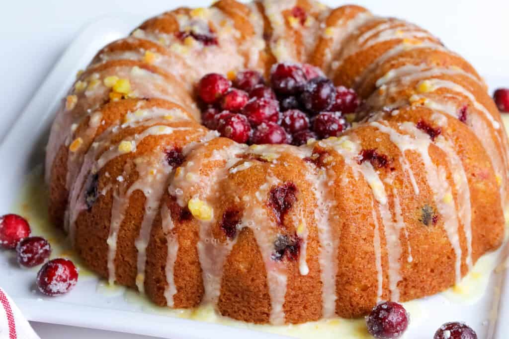 bundt cake topped with sugared cranberries and orange glaze