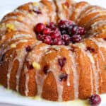 bundt cake topped with sugared cranberries and orange glaze