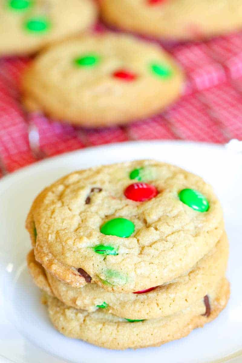 stack of three m&m cookies sitting on a white round plate.