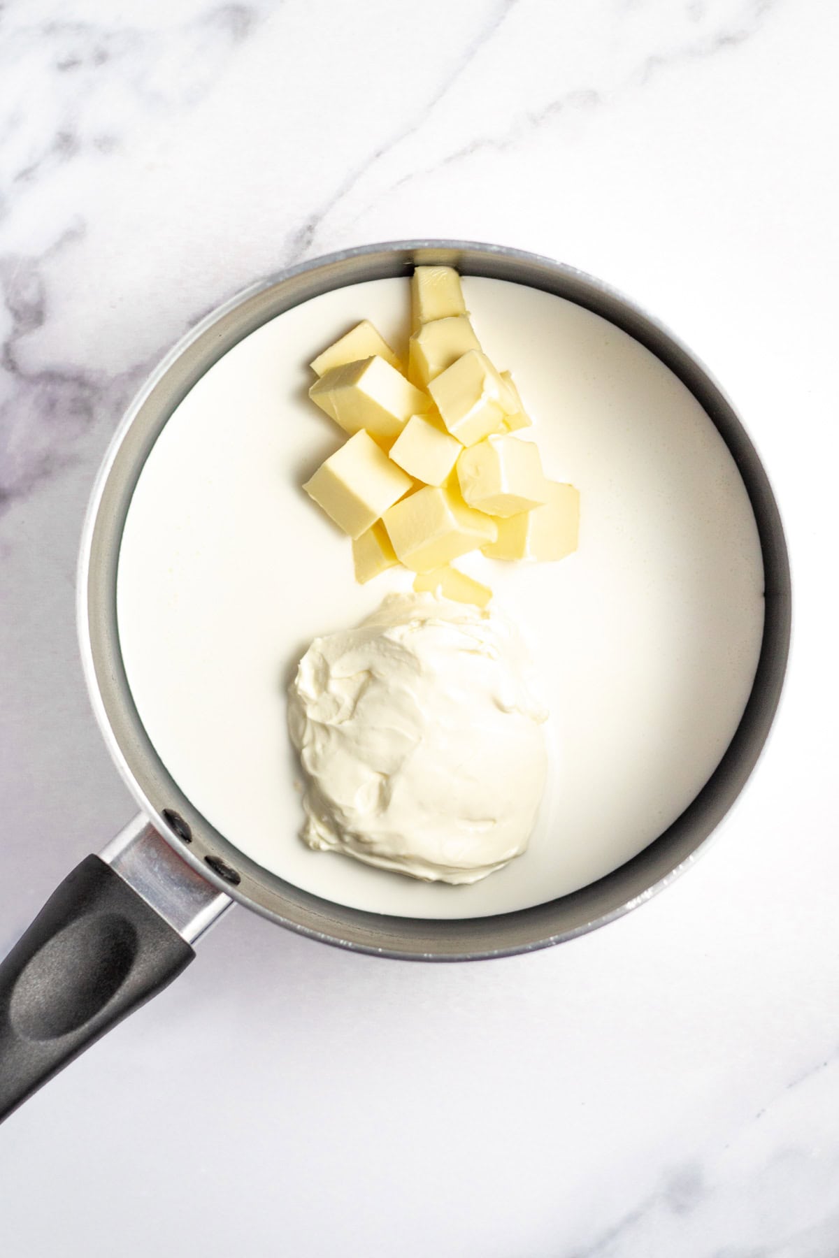 Butter and cream cheese added to pan of heavy cream.
