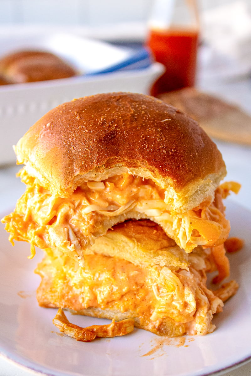 stacked buffalo chicken sliders on a plate the top slider has a bite taken out of it