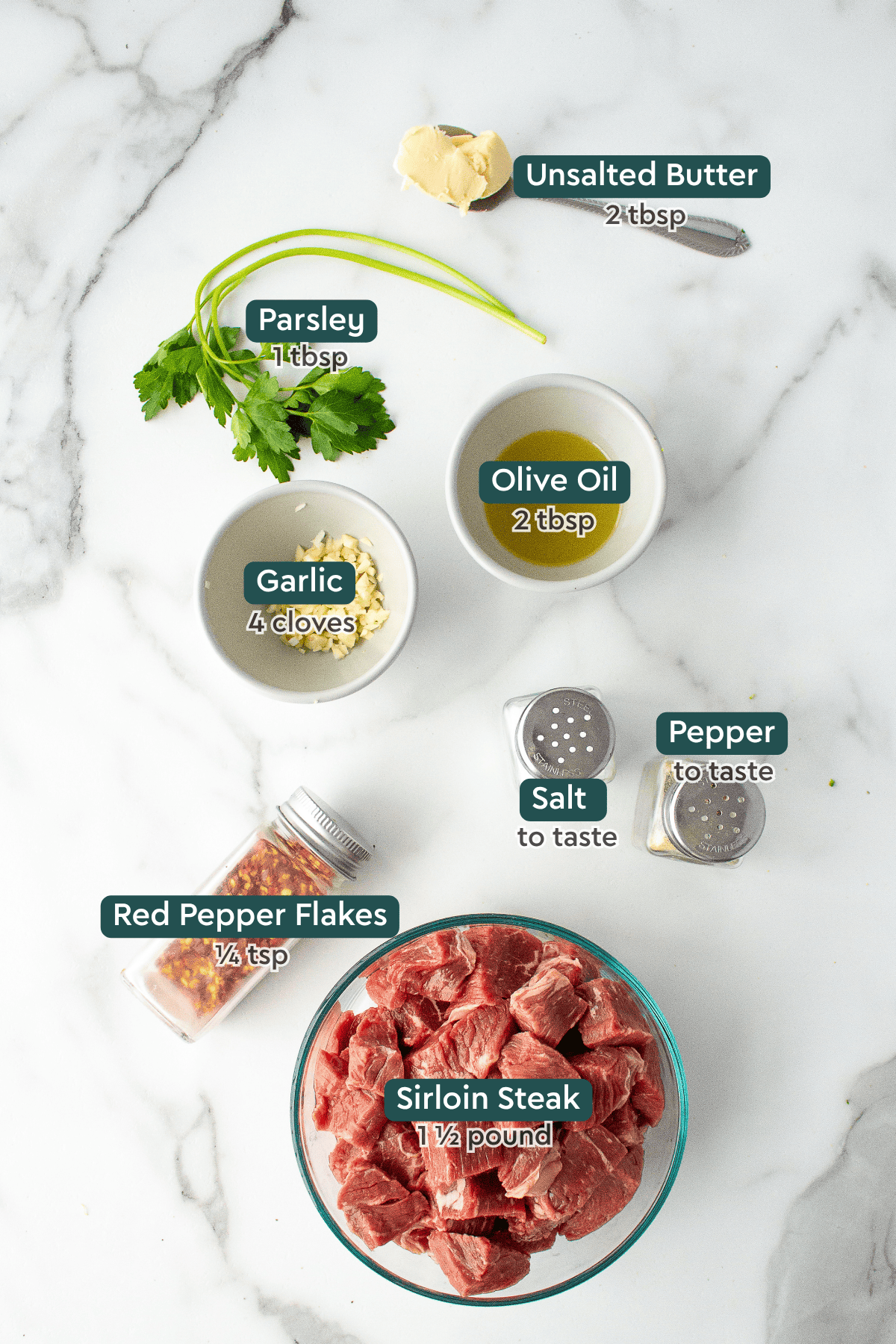 Ingredients for garlic butter steak bites, including butter, parsley, olive oil, garlic, salt, pepper, red pepper flakes, sirloin.