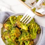 roasted broccoli on a silver fork served on a white plate