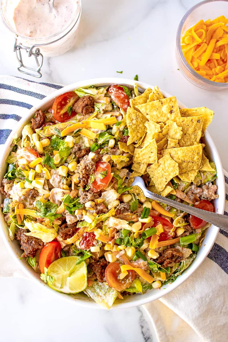 taco salad mixed in a white bowl served with corn tortilla chips