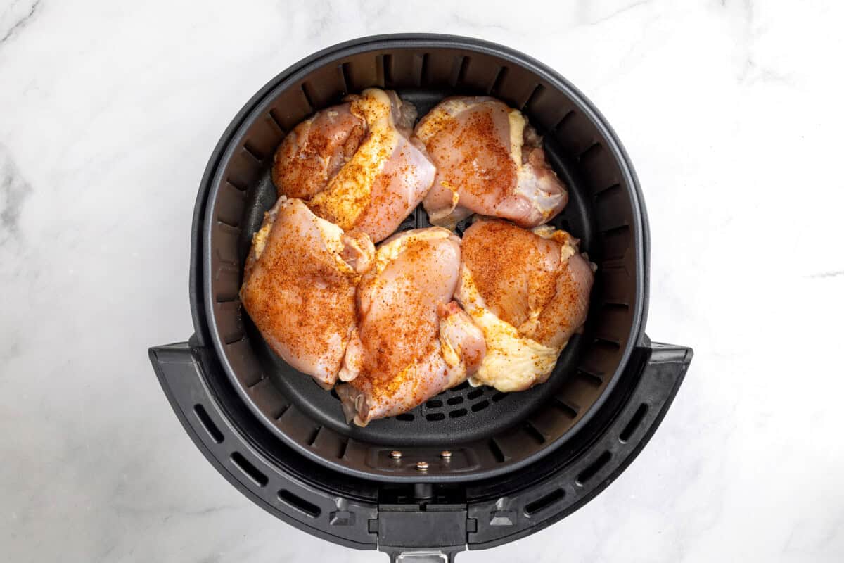 Boneless skinless chicken thighs in air fryer before cooking.