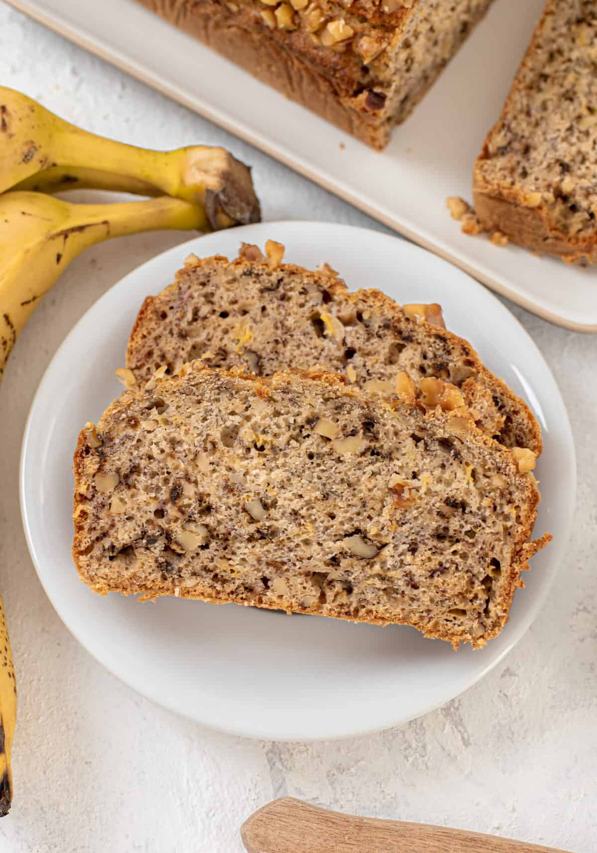 two slices of banana walnut banana bread on a white round plate
