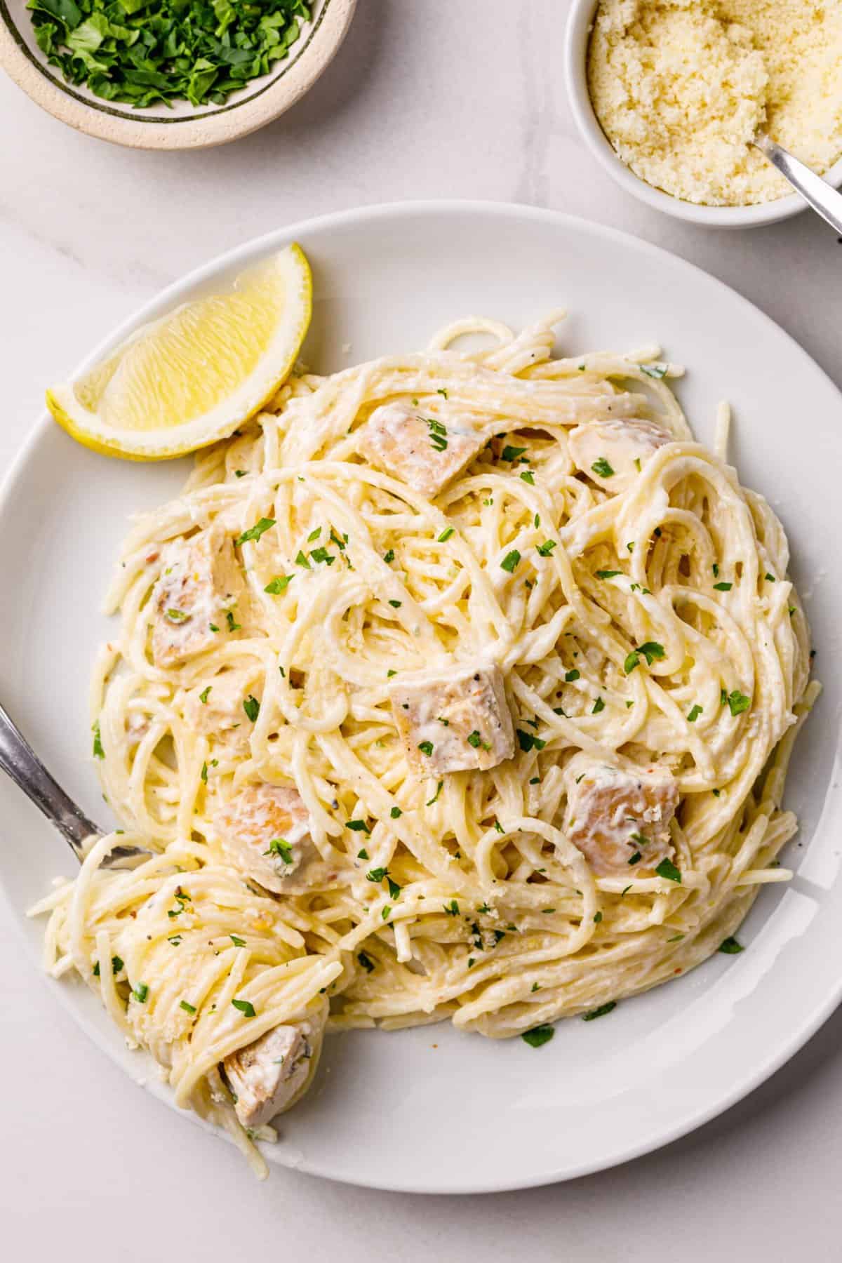 creamy lemon chicken pasta served on a white round plate with a silver fork