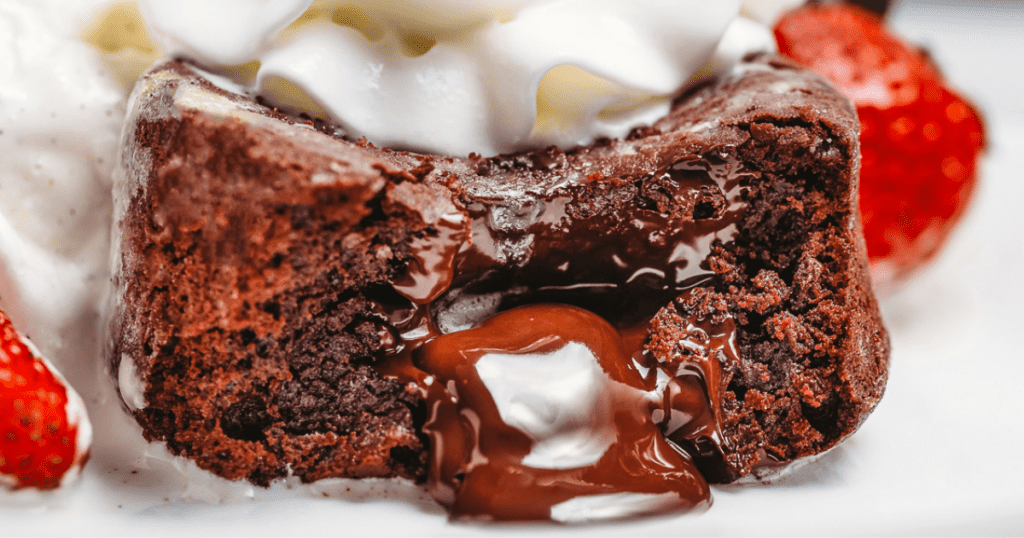 inside of a chocolate molten lava cake made from scratch topped with whipped cream and strawberries
