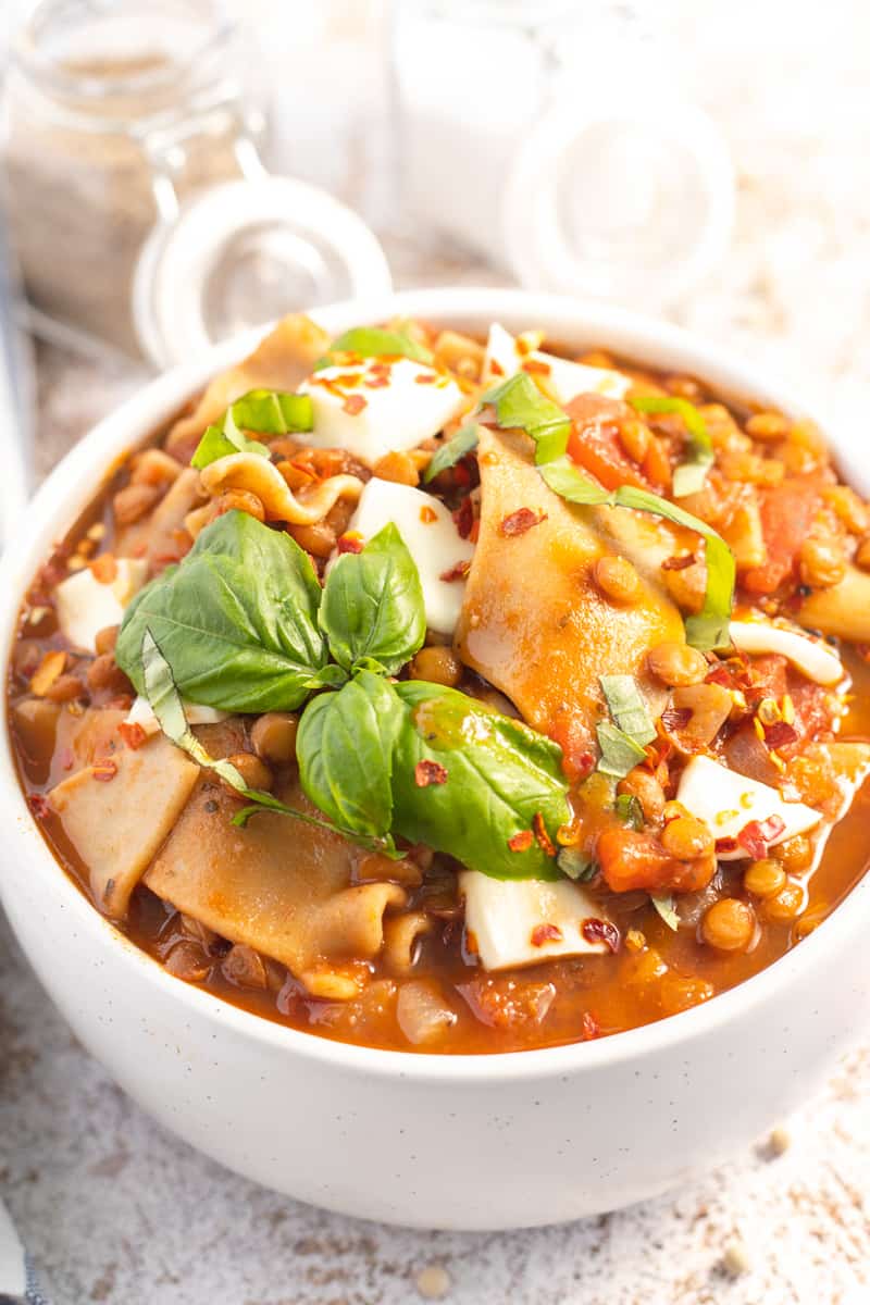 close up image of a bowl of instant pot lasagna soup topped with fresh basil as a garnish