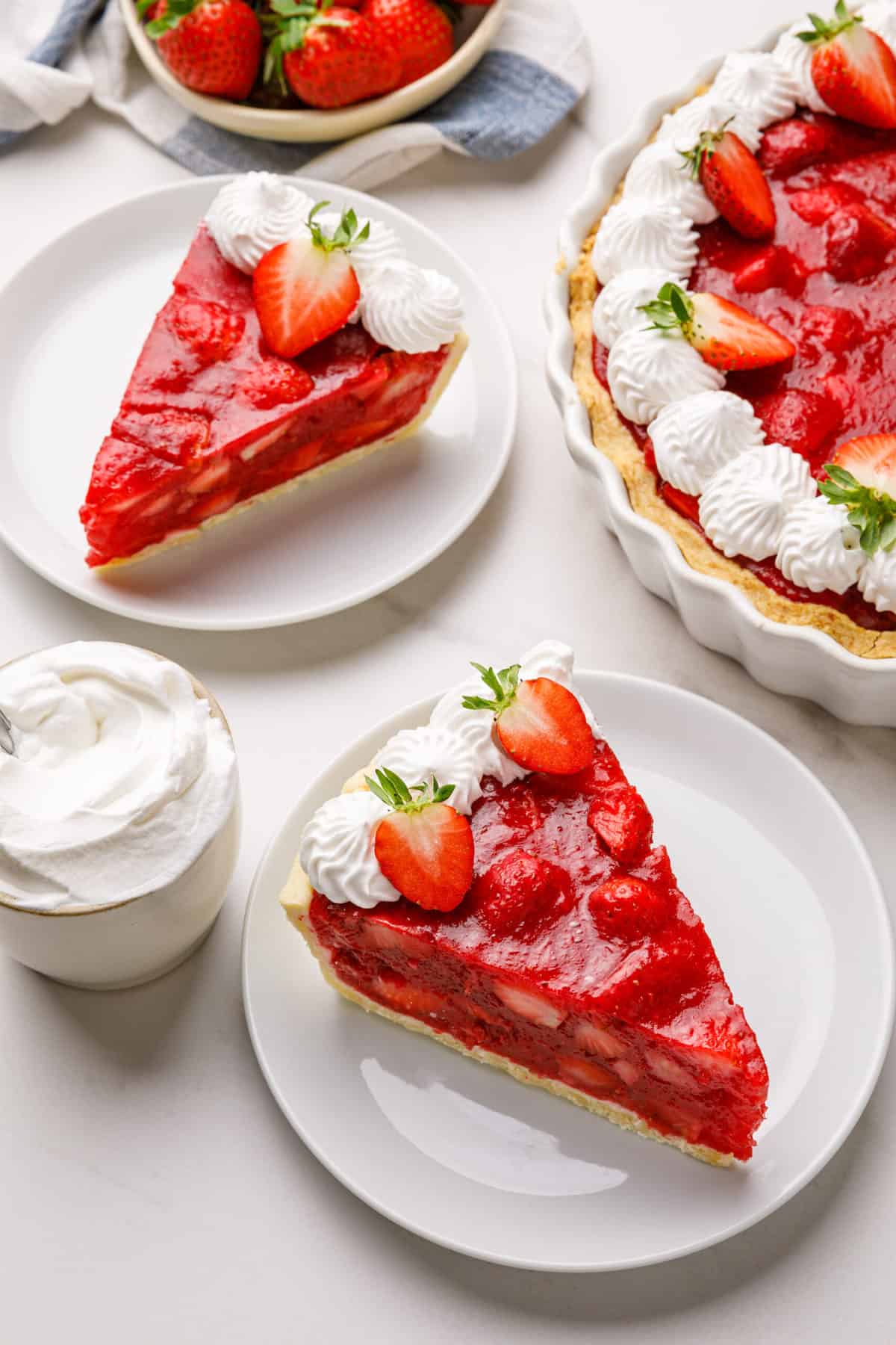slice of classic strawberry pie with chantilly cream served on a white round plate