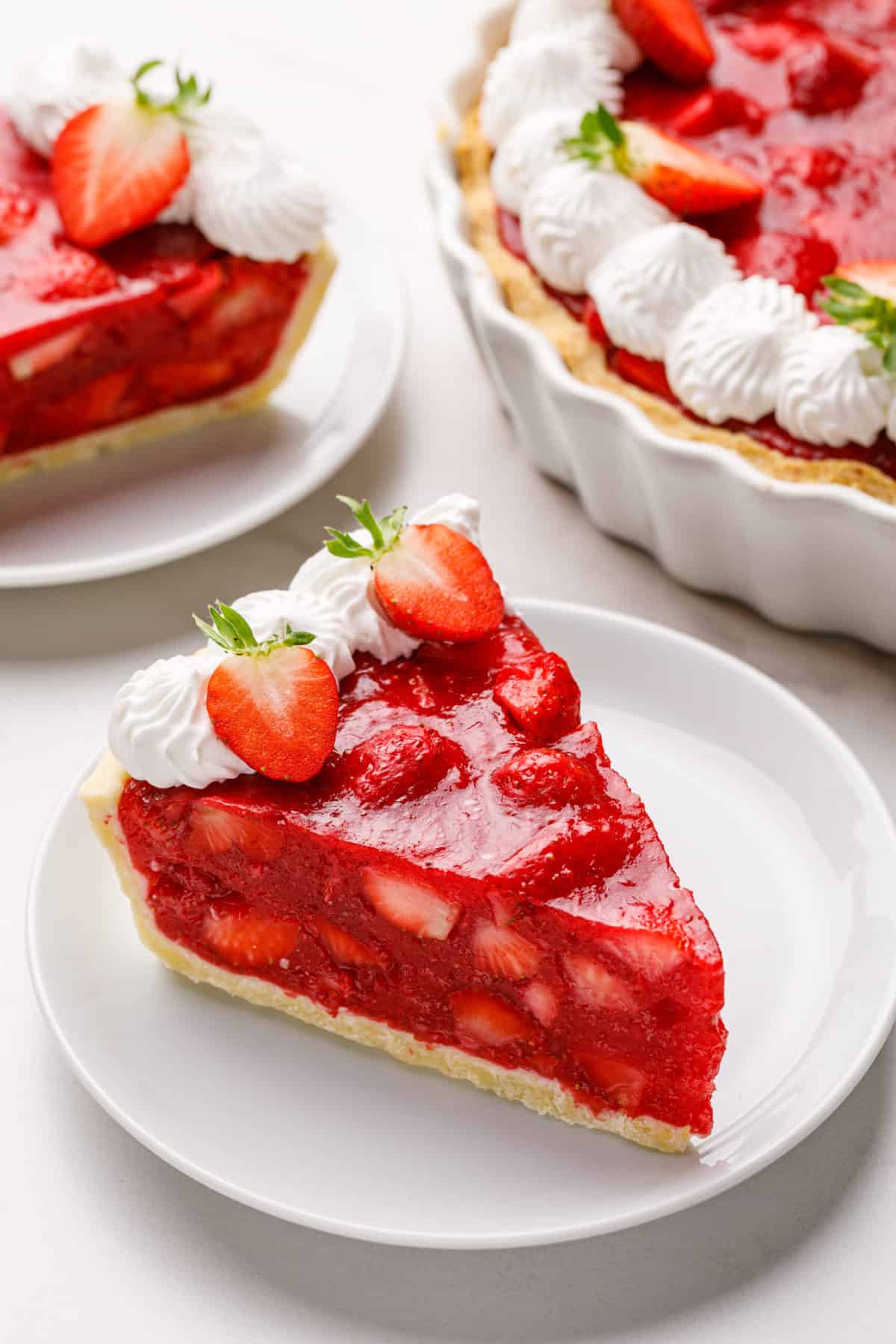 slice of strawberry pie topped with halved strawberries and chantilly cream