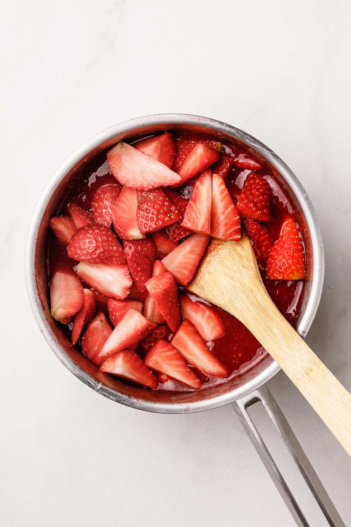 Top down images of strawberries, cooking in a saucepan.