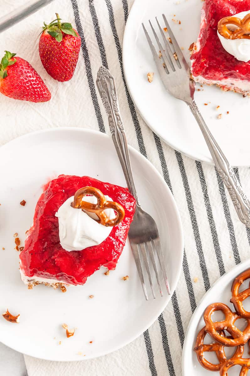 serving of strawberry pretzel dessert  topped with whipped cream and a pretzel on top served on a plate