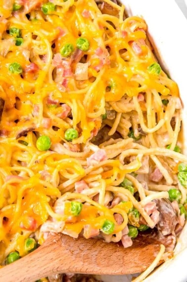 A wooden spoon scooping up ham tetrazzini.