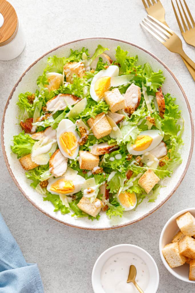 Caesar salad with grilled chicken breast, hard-boiled egg, croutons, parmesan cheese, green salad lettuce and dressing.