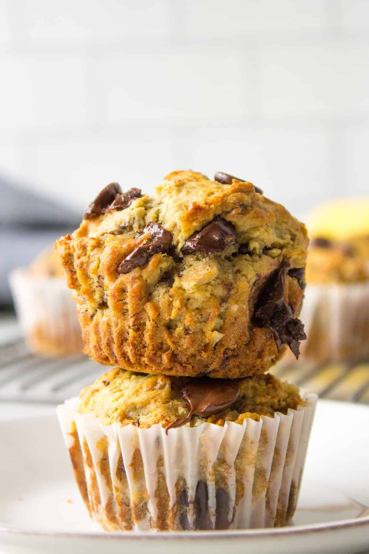 two banana chocolate chip muffins stacked on a plate