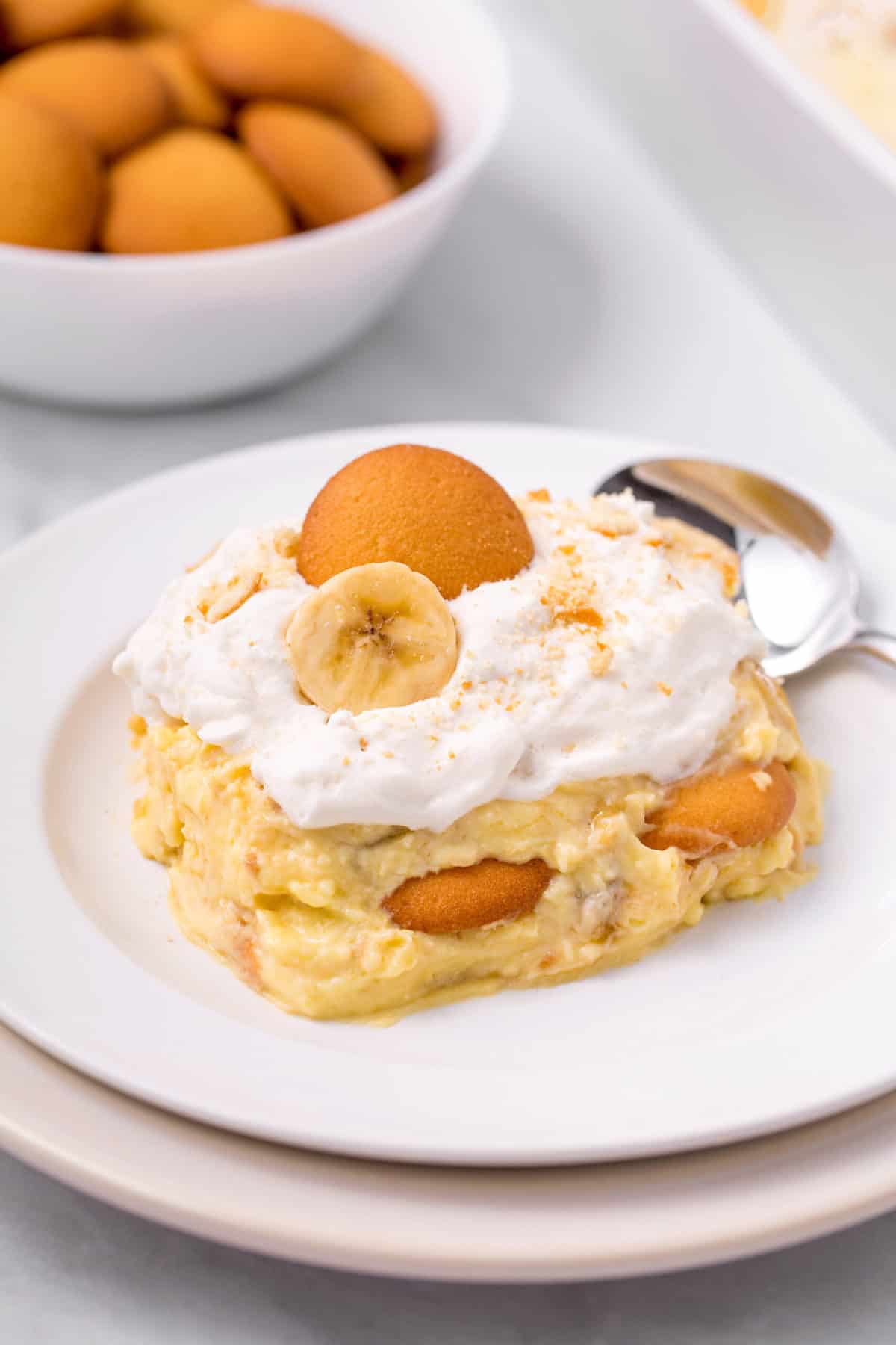 serving of layered banana pudding on a white plate with a silver spoon
