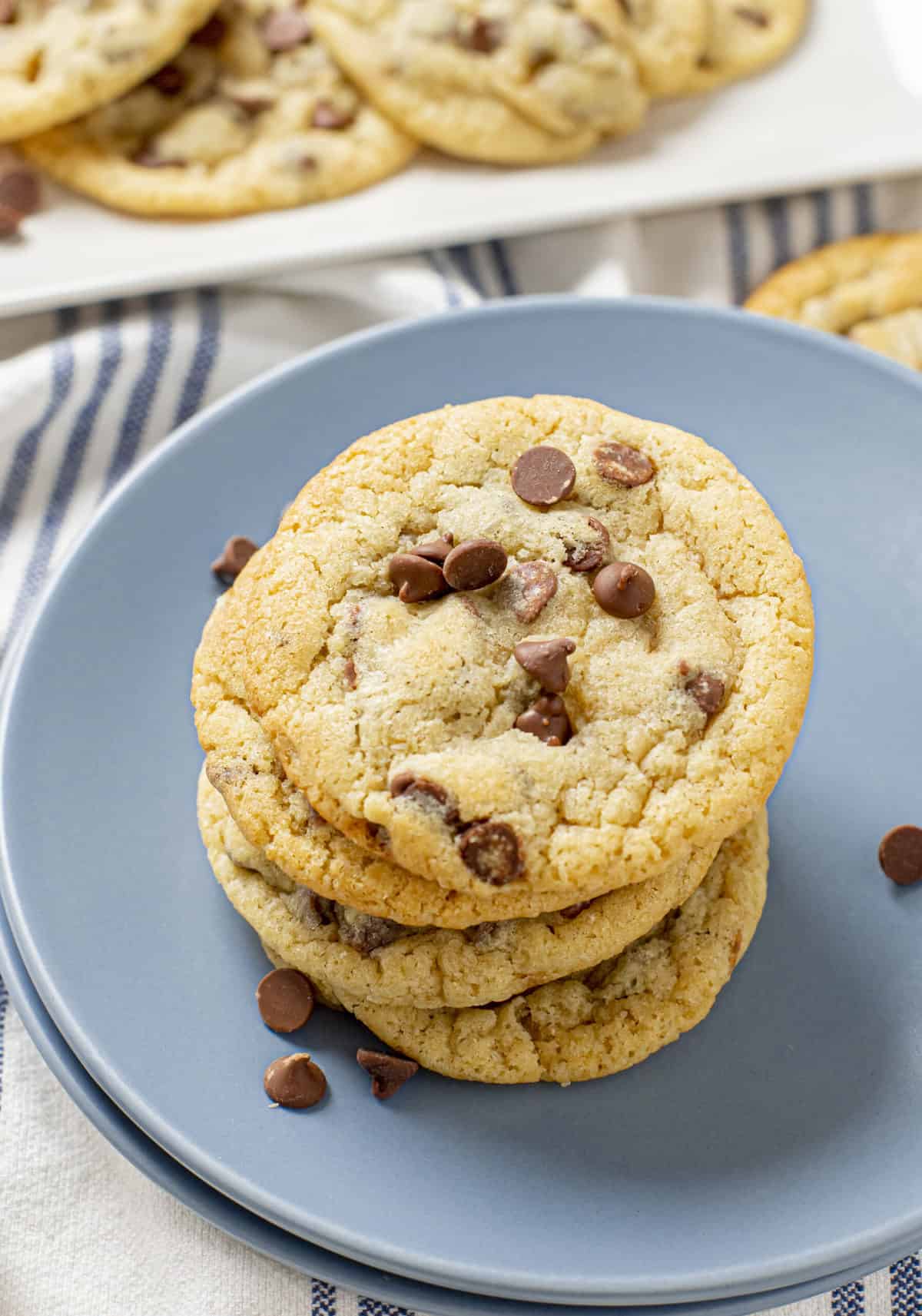 stack of four chewy chocolate chip cookies served on a blue round plate