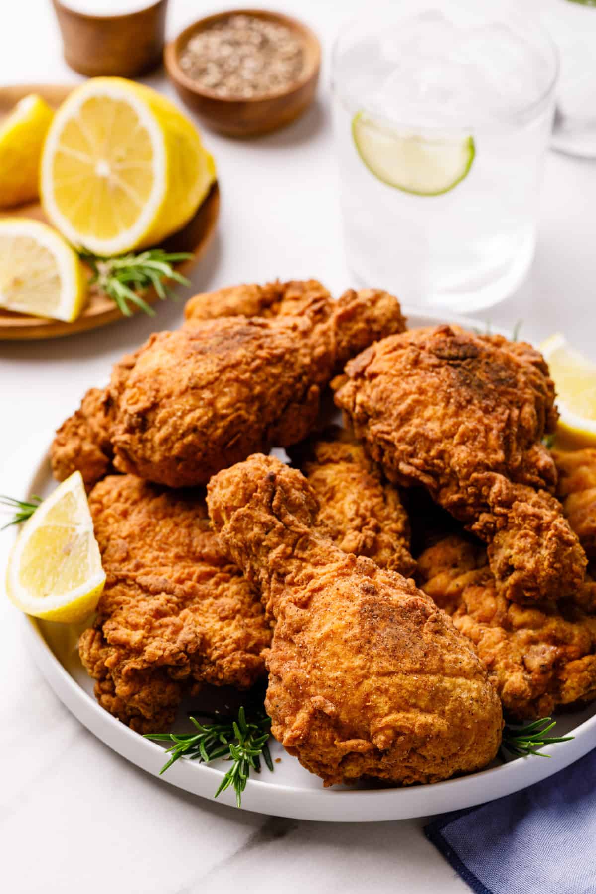 top down view of a plate of drumstick fried chicken garnished with rosemary and sliced lemon