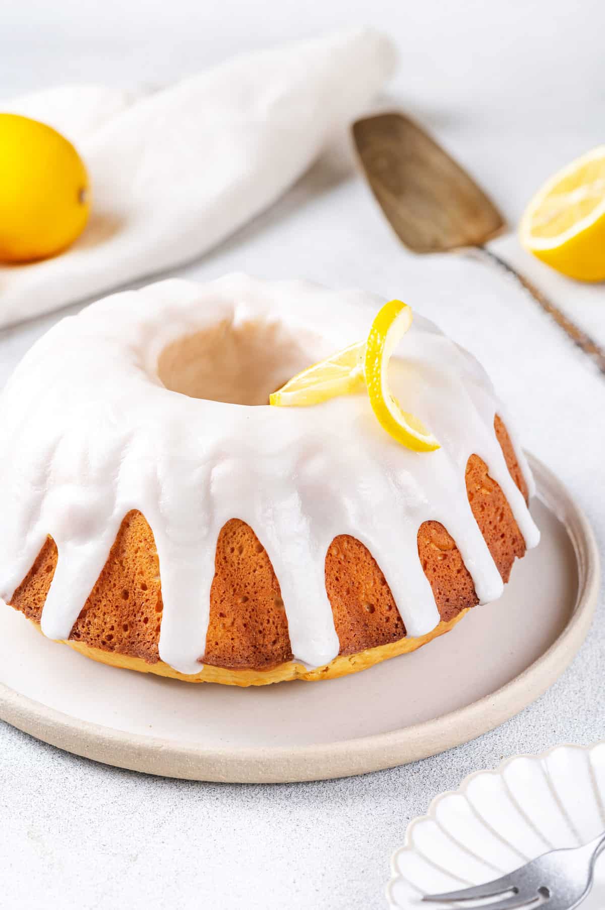 lemon bundt pound cake with lemon glaze topped with sliced lemon served on a plate