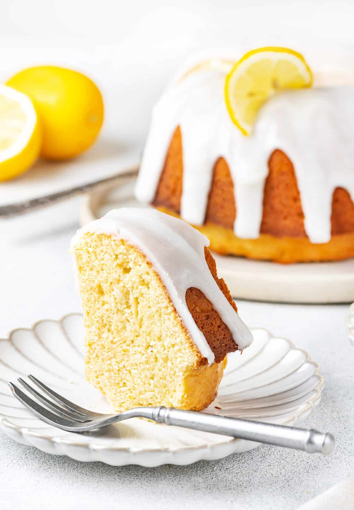 slice of lemon pound cake with lemon glaze served on a white plate with a silver fork