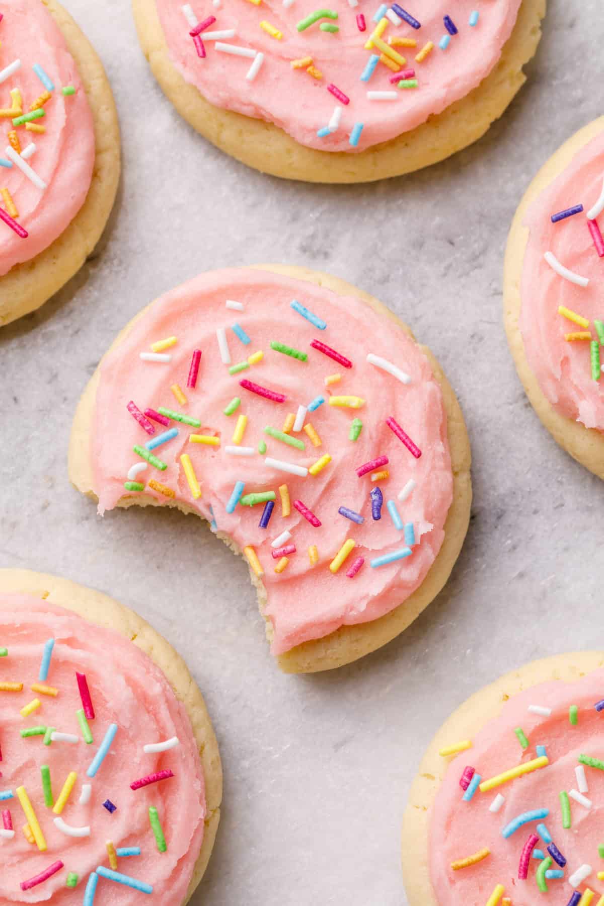 a bite taken out of a copycat lofthouse cookie with pink frosting and rainbow sprinkles