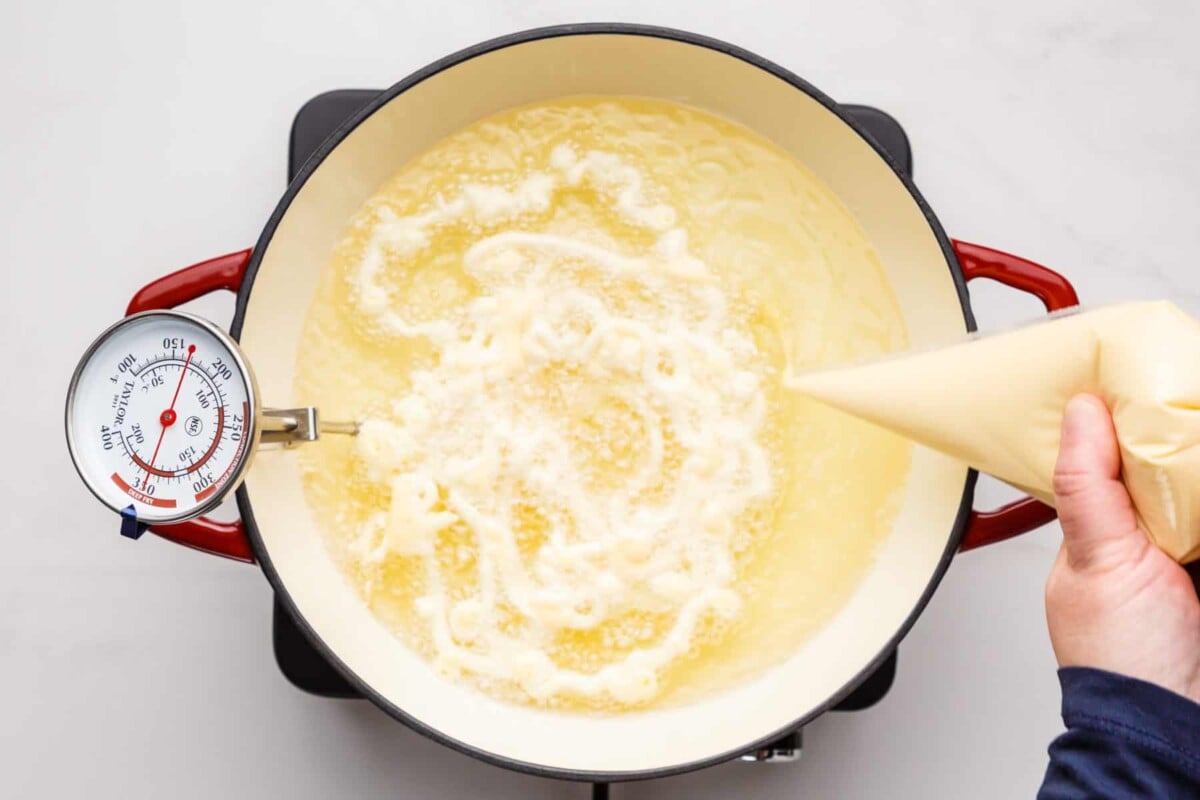Piping pancake mix into funnel cake.